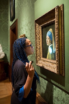 Abbie Vandivere Abbie Vandivere står och tittar på tavlan Flickan med pärlöränge. Foto: Ivo Hoekstra, Mauritshuis