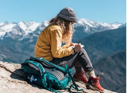 Girl sitting on a mountain reading a book. Photo by Tyler Nix on Unsplash