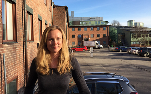 Elisabeth Niklasson framför en tegelbyggnad, och i bakgrunden syns en bilparkering.