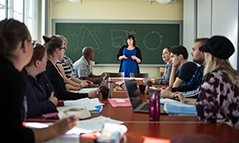 Lärare i undervisningssituation. Studenter runt ett bord.