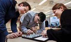 Smiling students, heads close around a sience experiment